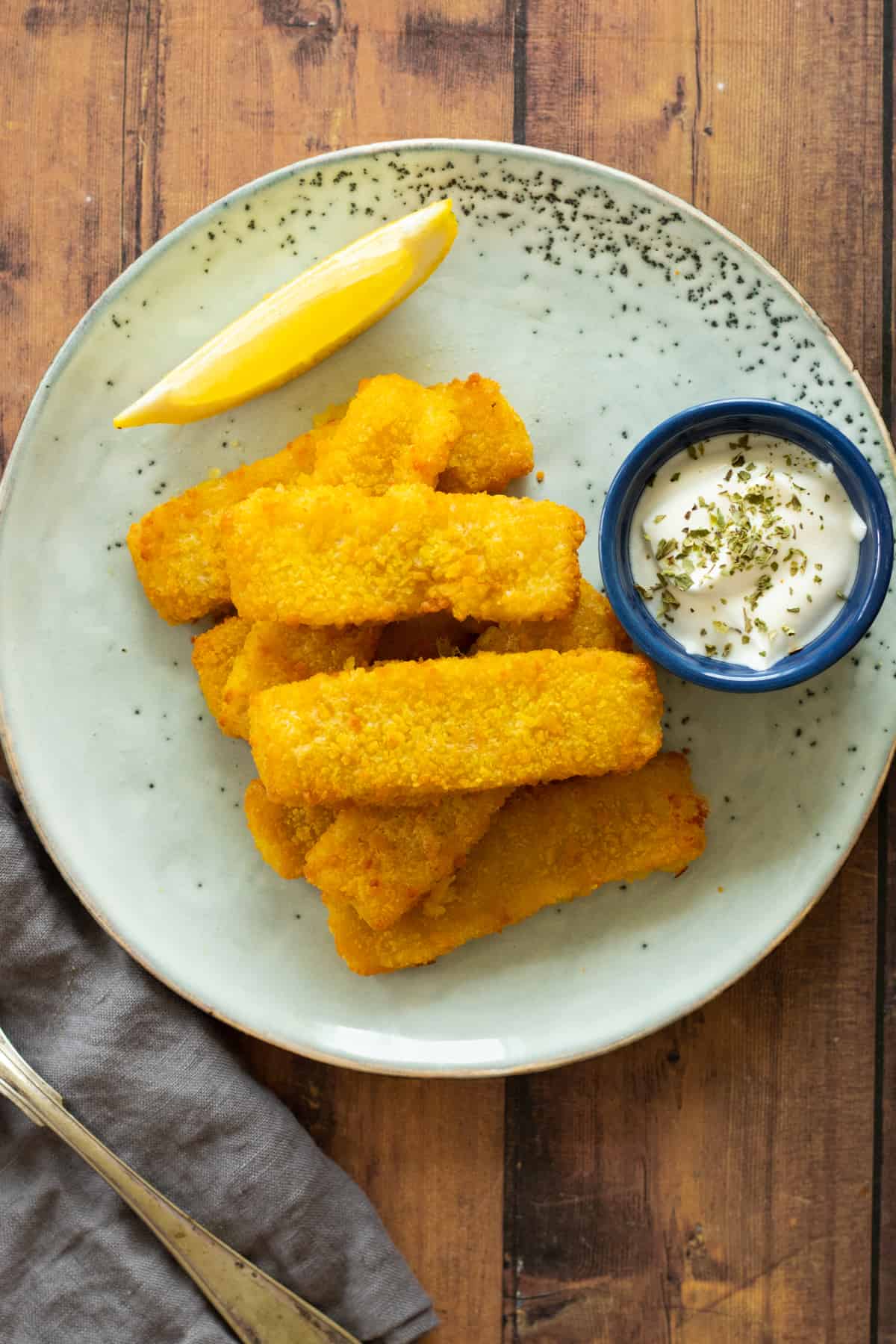 air fried fish sticks on a blue plate with dipping sauce.