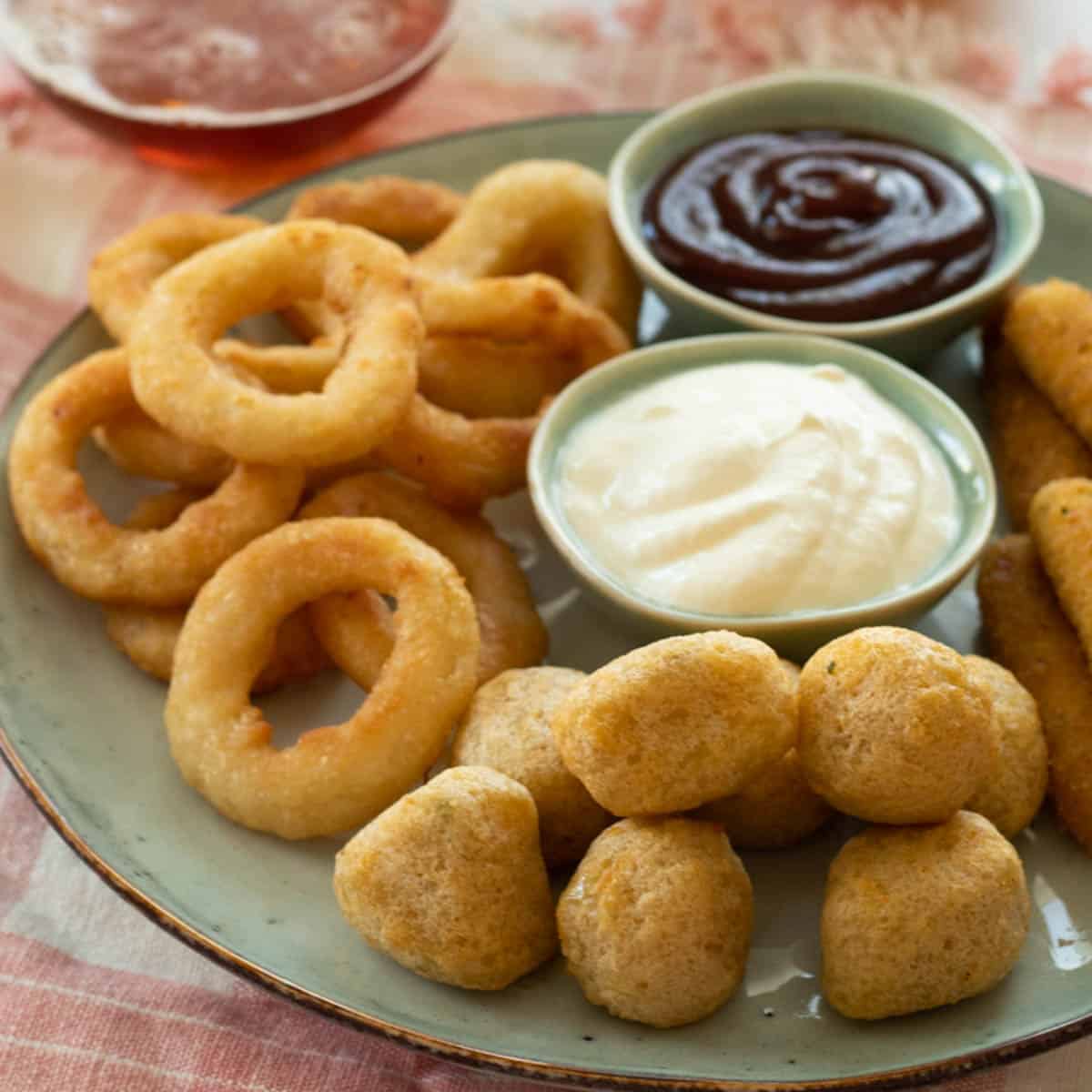 Air fried frozen foods on a plate with dipping sauces.
