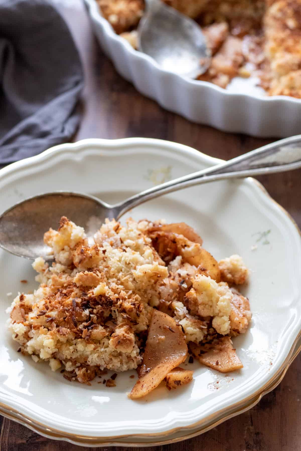 apple crisp without oats on a white plate with a spoon.