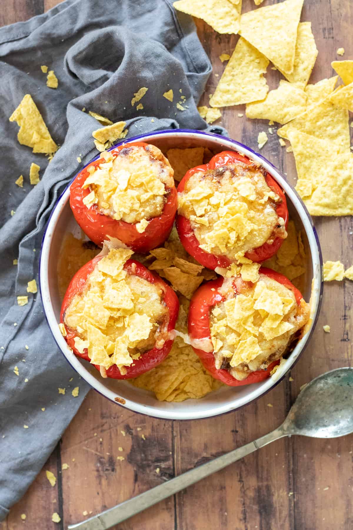 four stuffed bell peppers without rice in a baking dish, topped with tortilla chips