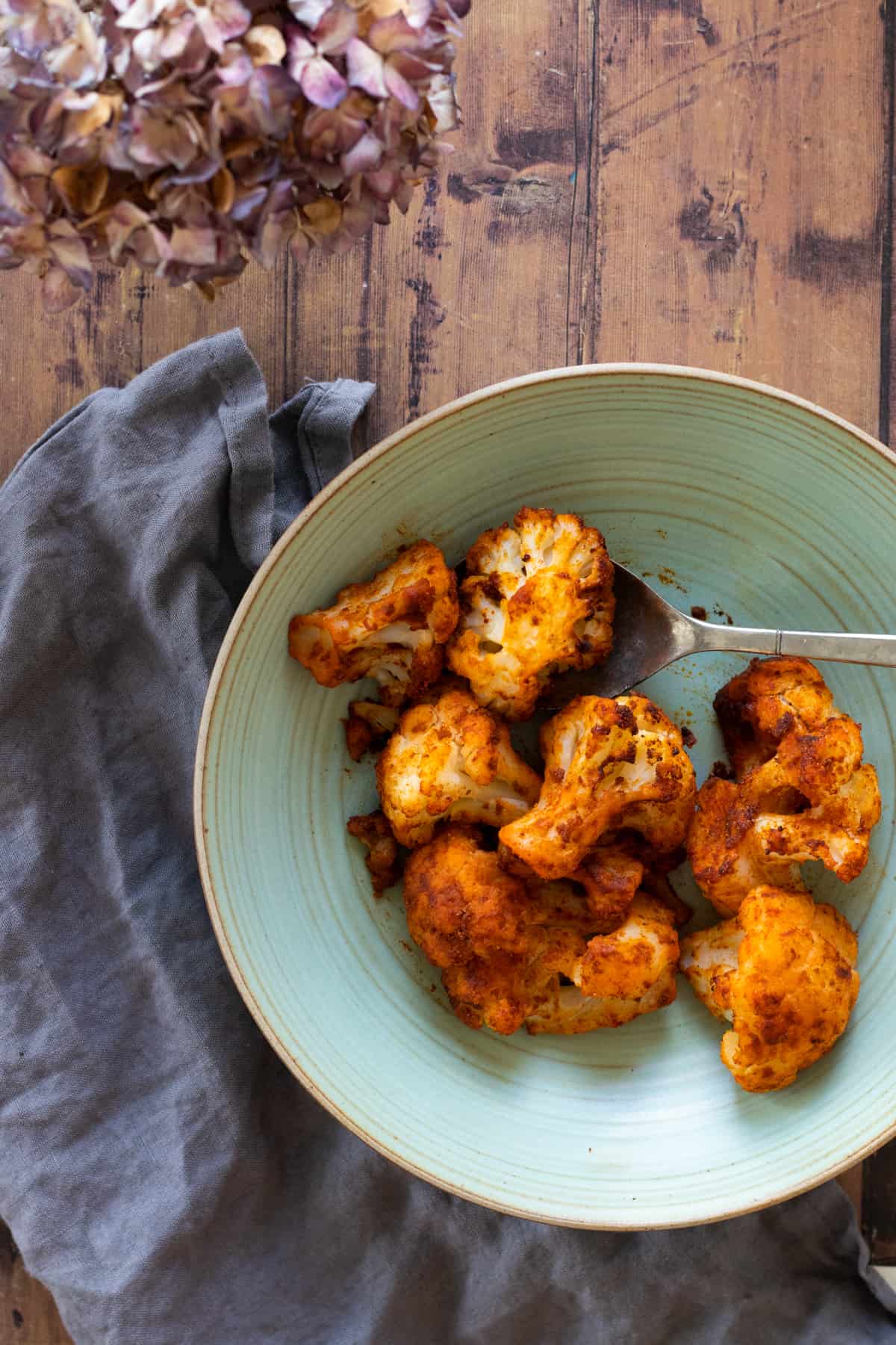 air fried seasoned cauliflower on a green plate.