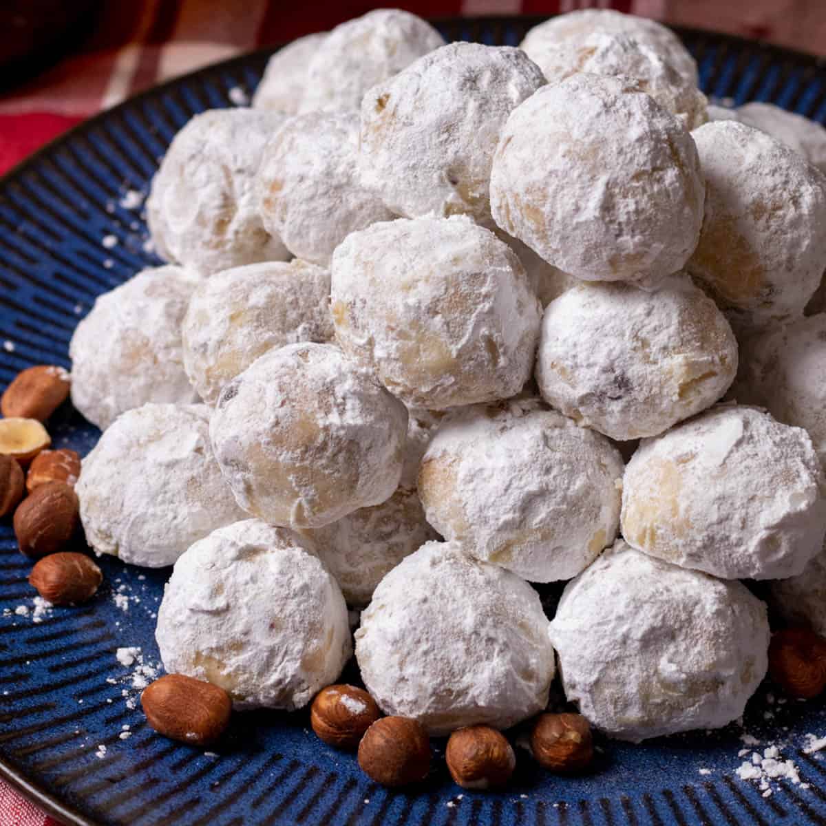 Butterball cookies on a blue plate with hazelnuts.