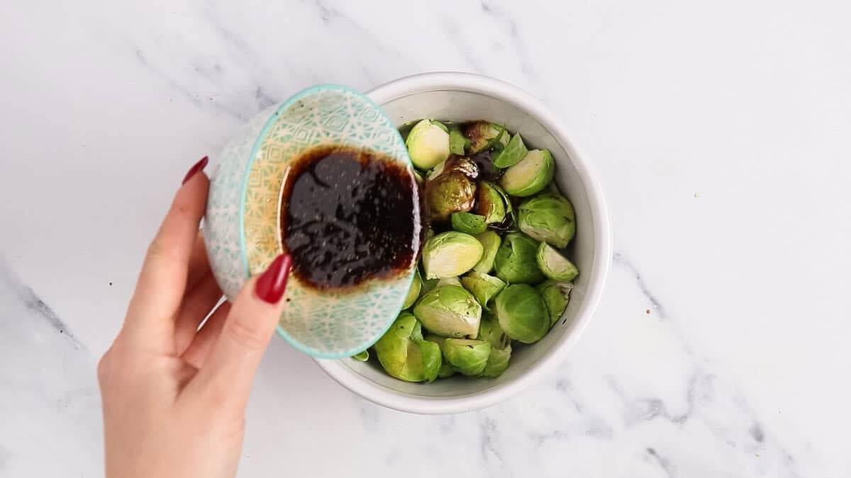 Pouring vinaigrette over brussels sprouts.
