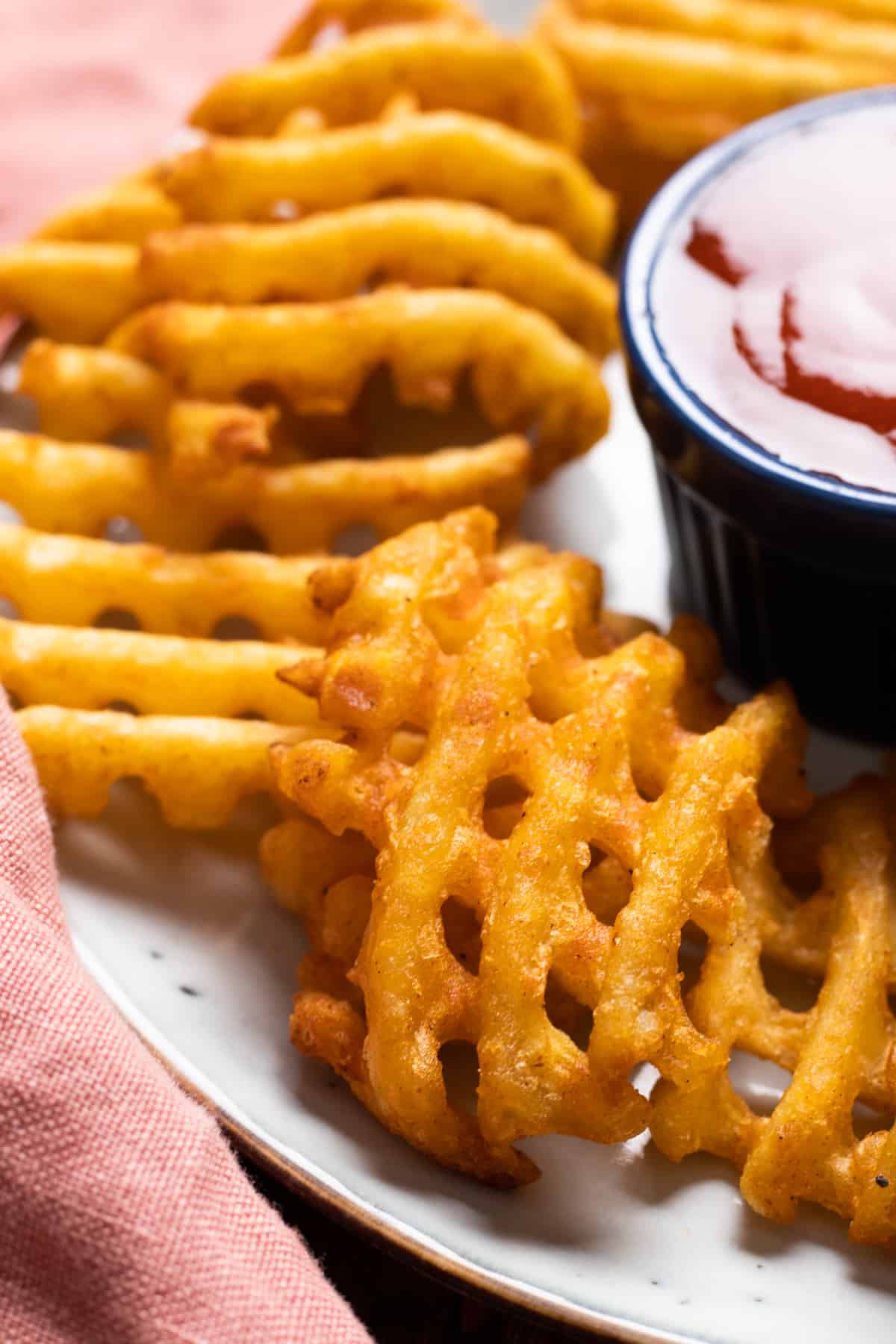 waffle fries on a blue plate with red dipping sauce