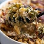 A spoonful of chicken broccoli pasta bake being lifted up out of a casserole.