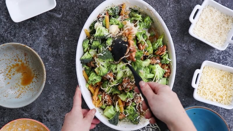 Mixing together ingredients for chicken broccoli pasta bake.