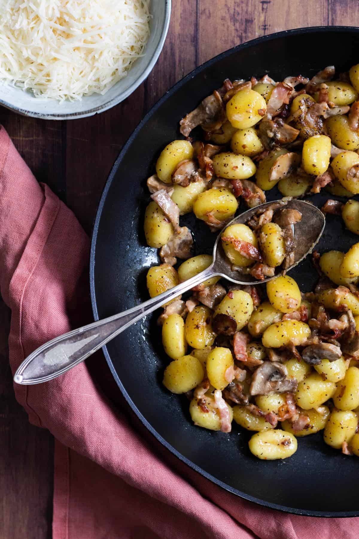 a pan full of creamy gnocchi with bacon and mushrooms