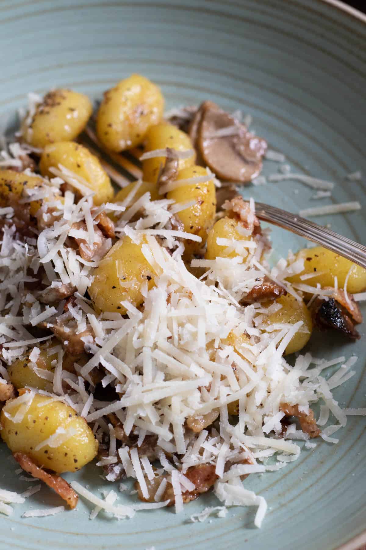 creamy gnocchi with bacon and mushrooms topped with parmesan cheese