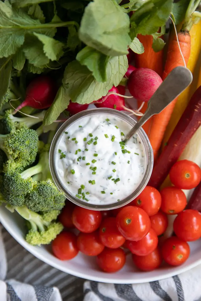 ranch dressing in a glass jar with veggies around it