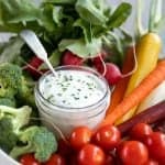 ranch dressing in a glass jar with veggies around it