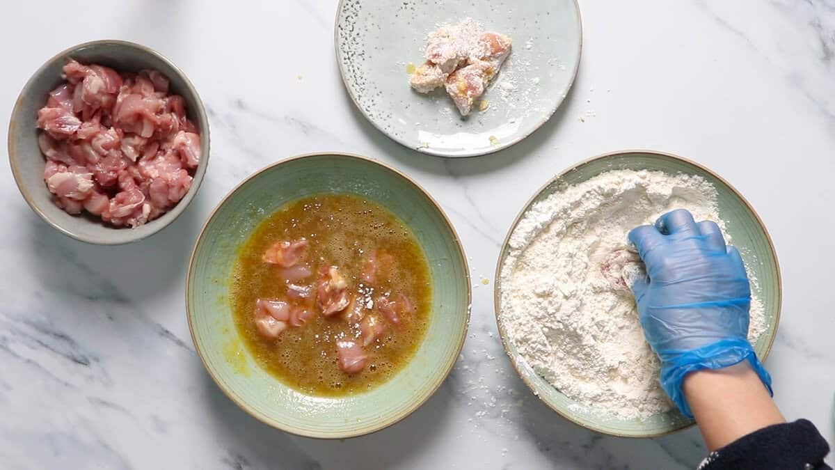 Dredging chicken in flour.