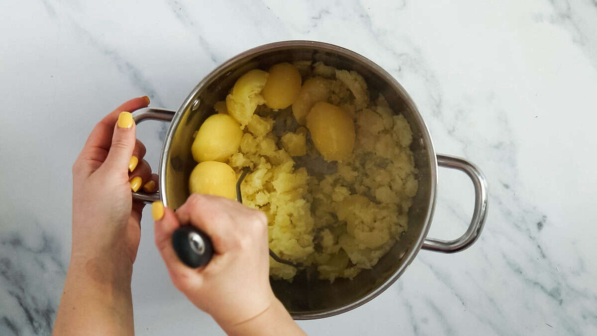 Mashing potatoes in a pot.