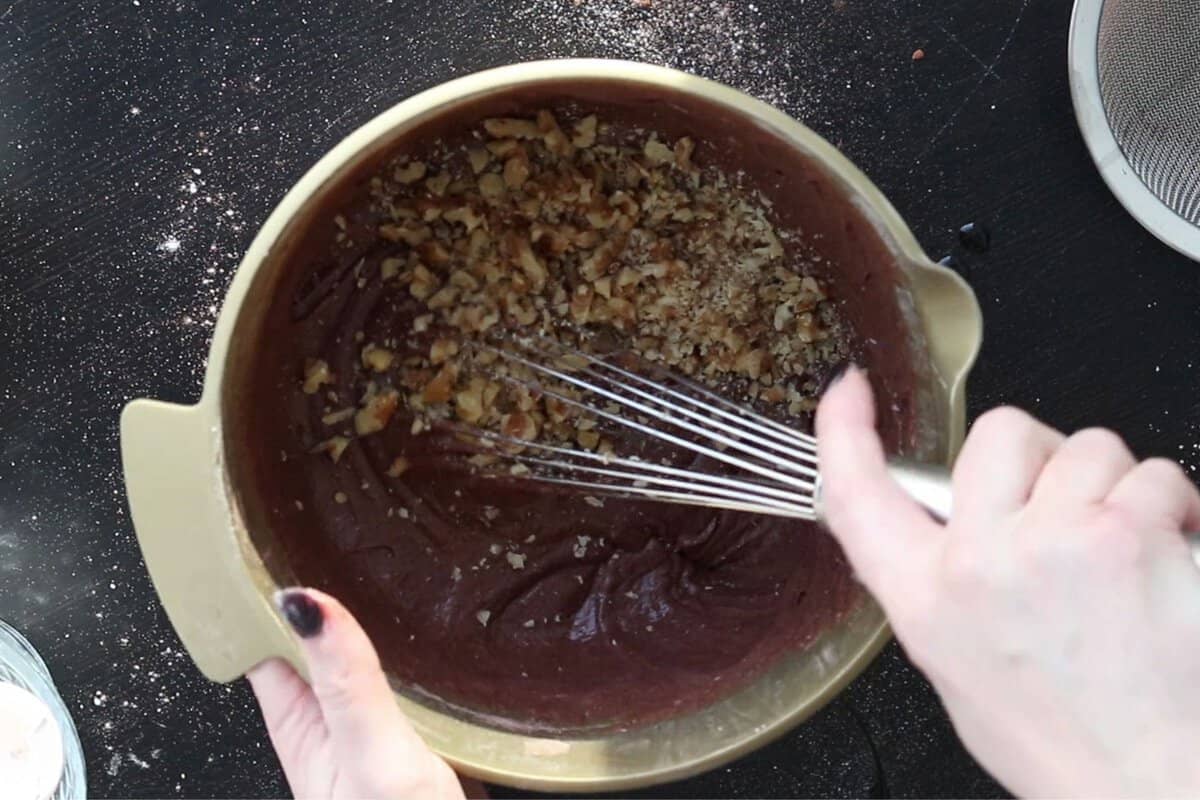 Adding walnuts to batter to make walnut brownies.