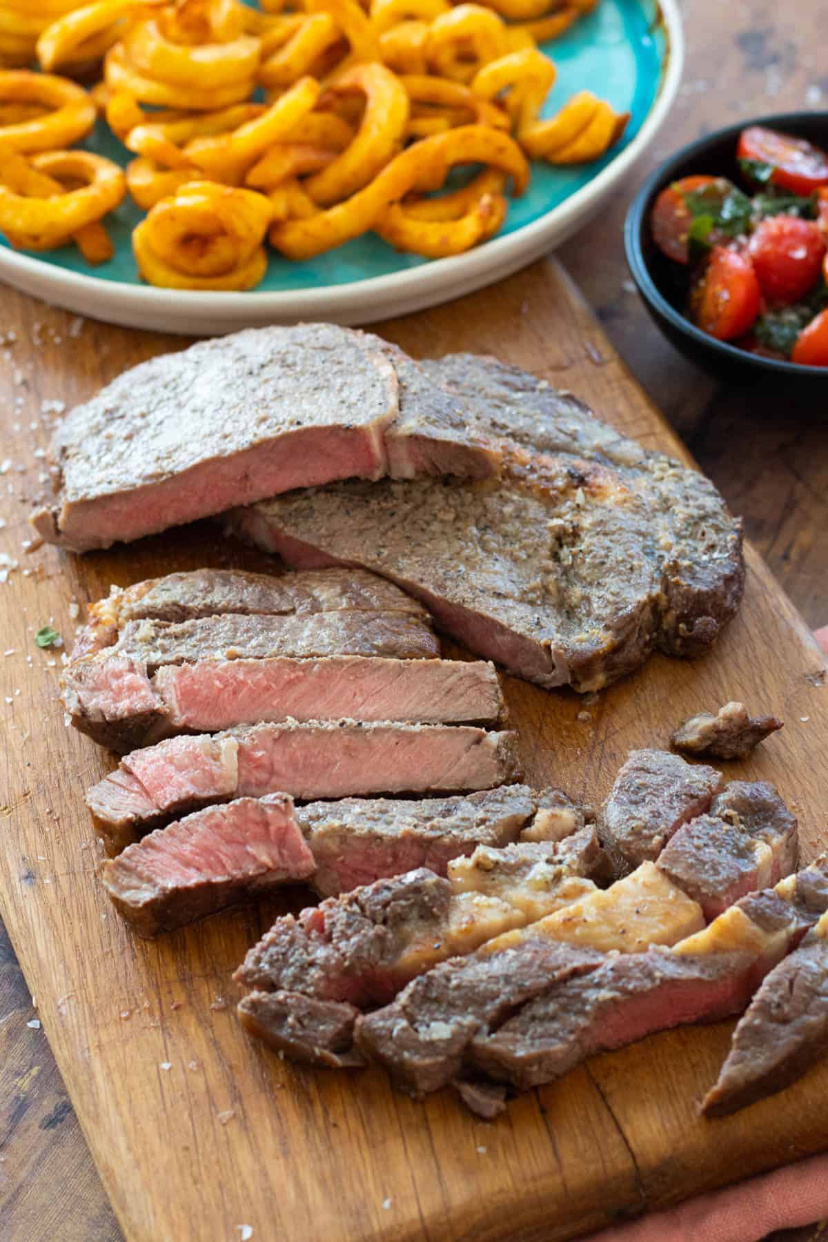 sliced steak on a wooden chopping board