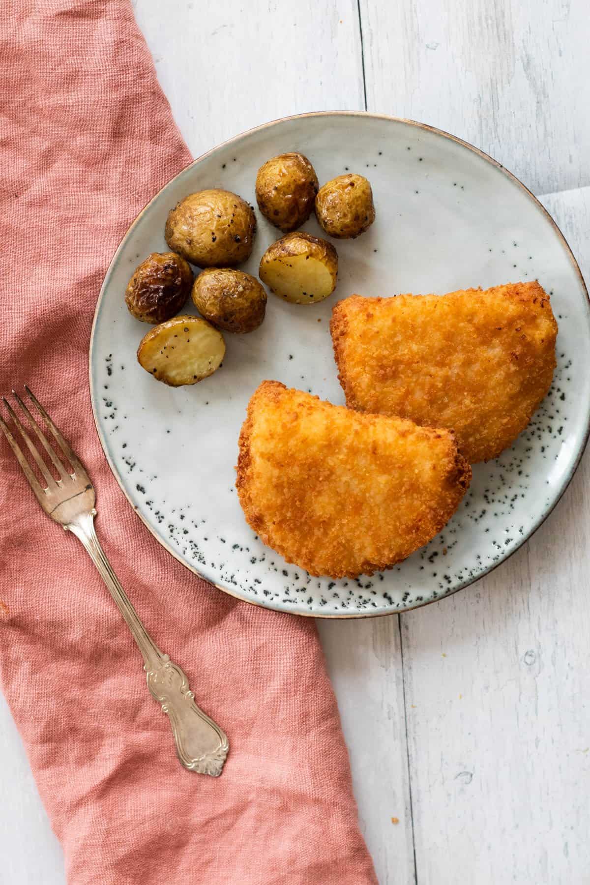 chicken cordon bleu on a plate with some potatoes.