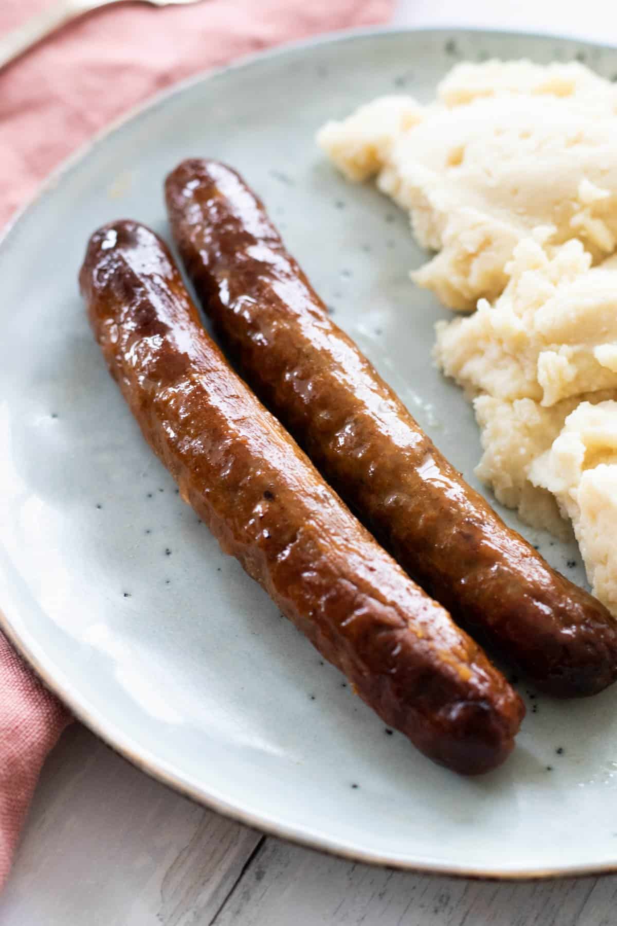 two sausages next to mashed potatoes.