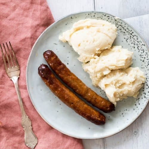 two sausages next to mashed potatoes.