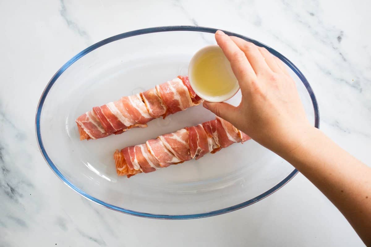pouring lemon juice over bacon wrapped salmon.