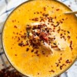 A bowl of creamy, spicy chicken soup topped with chili flakes.