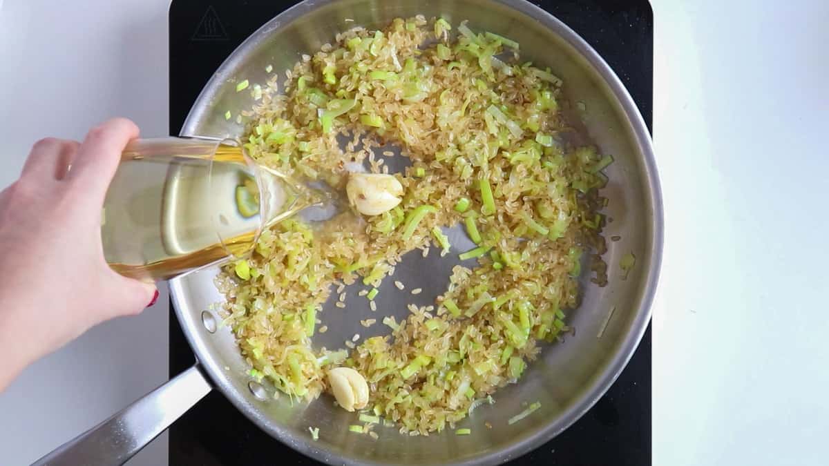 Adding white wine to risotto.