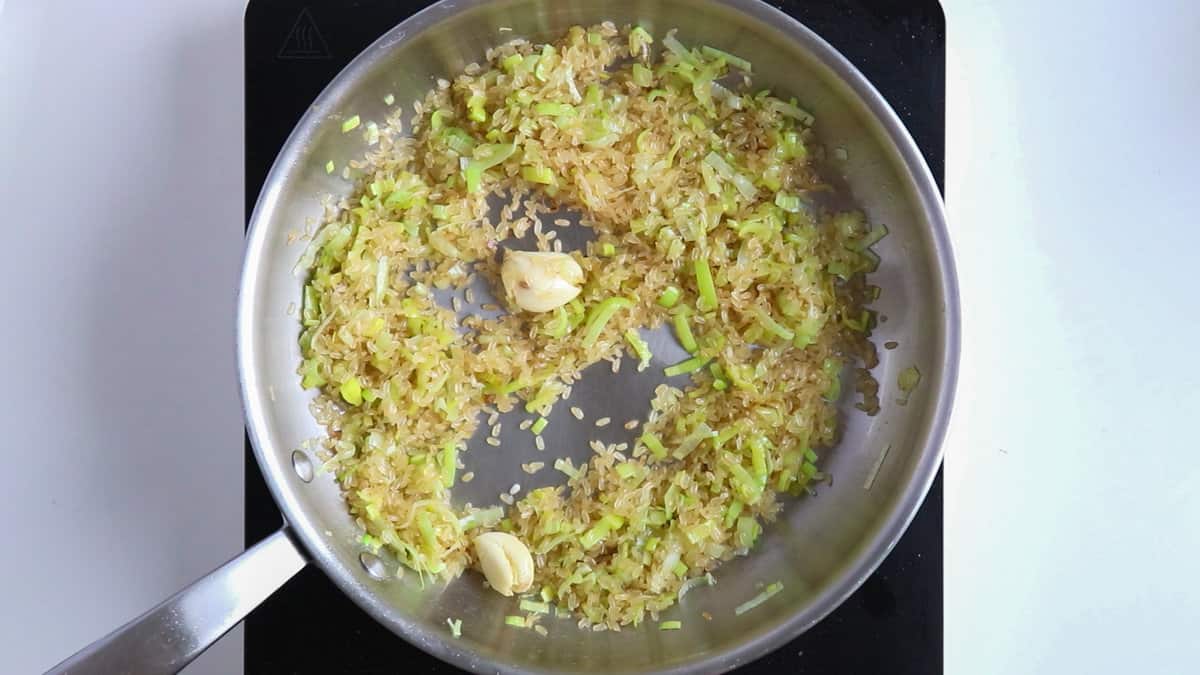 Cooking risotto rice with garlic and leeks.