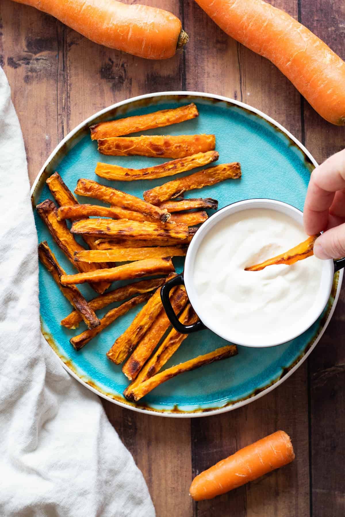 Carrot fries on a blue plate with a dipping sauce.