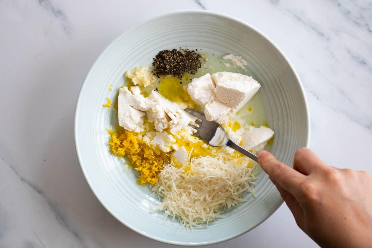 Mixing lemon ricotta pasta sauce with a fork.