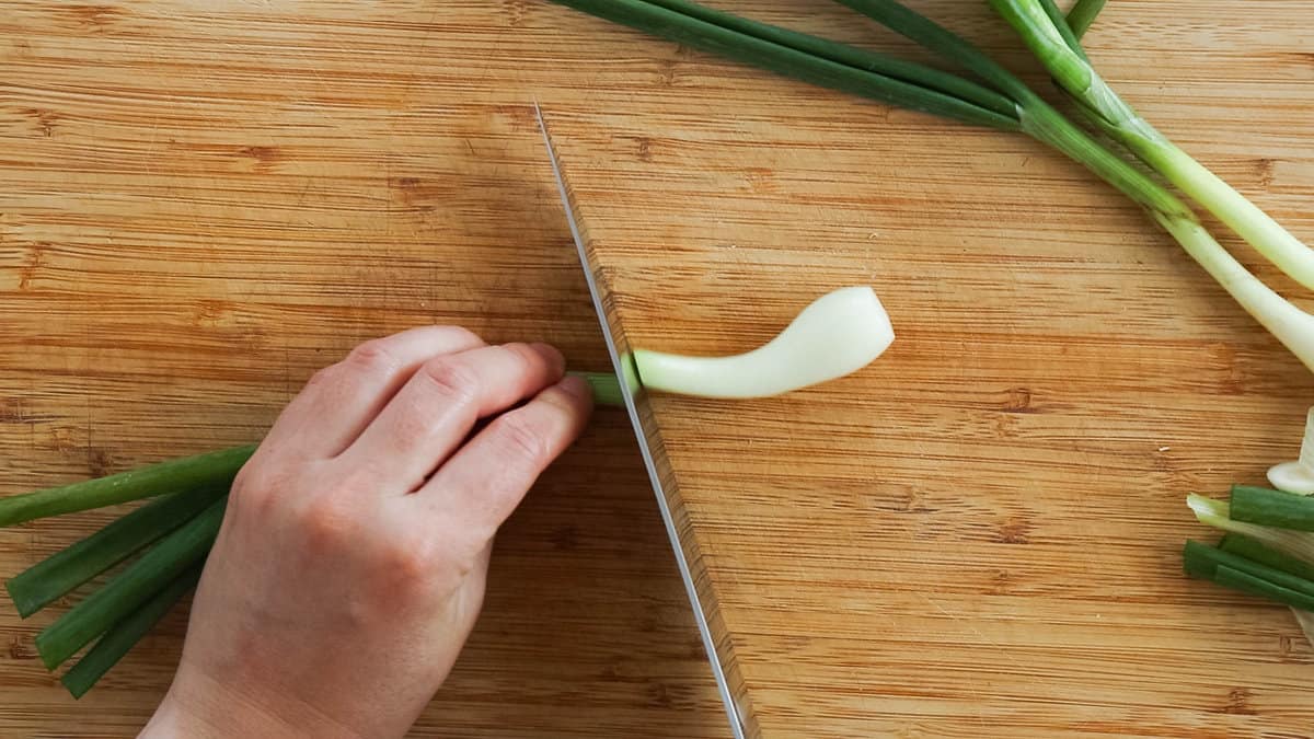 Separating the tops form the bulb of a green onion.