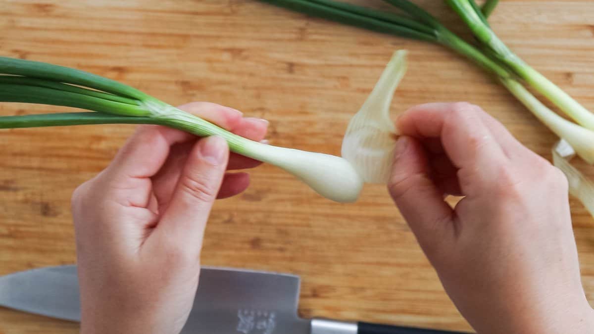 Removing the outer layer of a green onion.