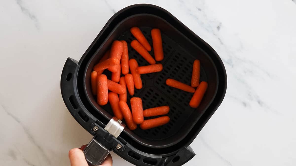 Baby carrots in air fryer basket.