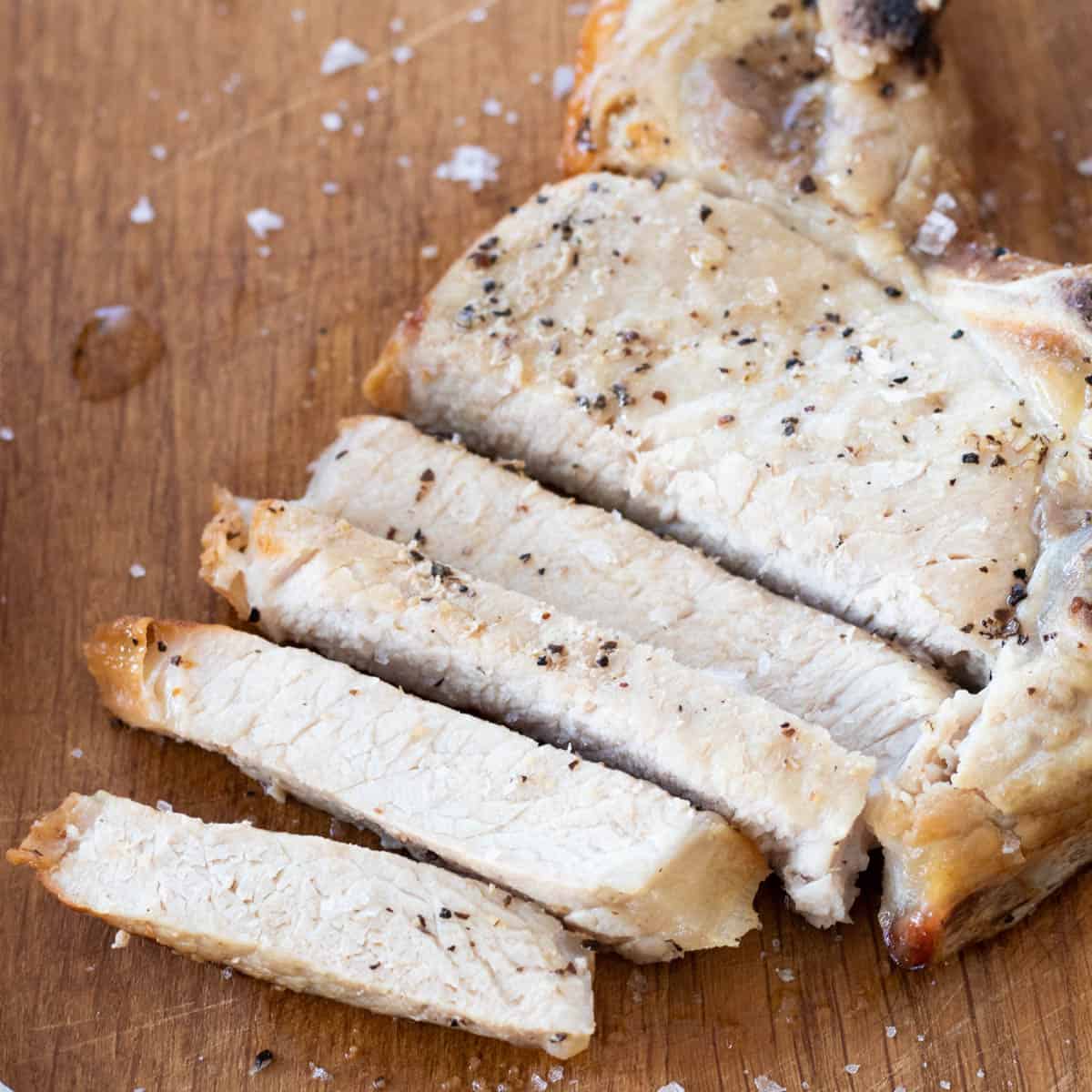 A sliced pork chop on a chopping board.