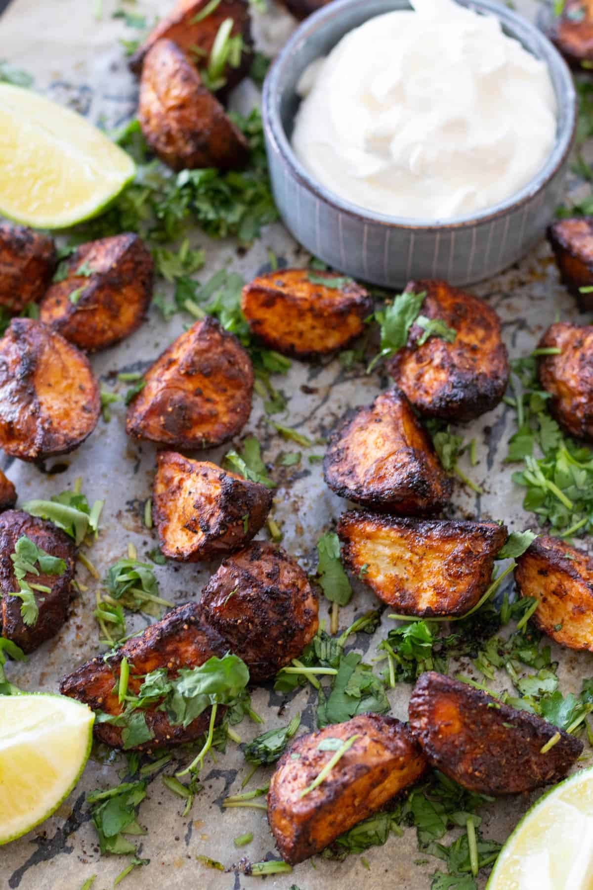 Mexican potatoes on a baking sheet with some lime wedges.