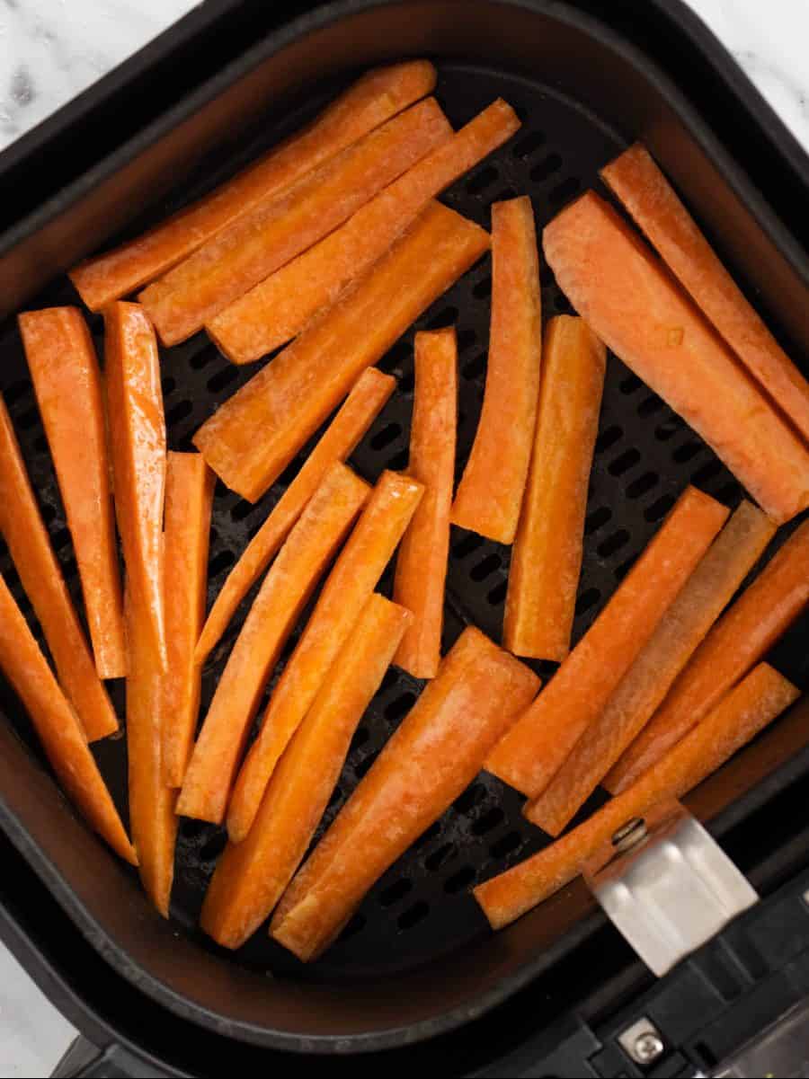 Carrot fries in air fryer basket.