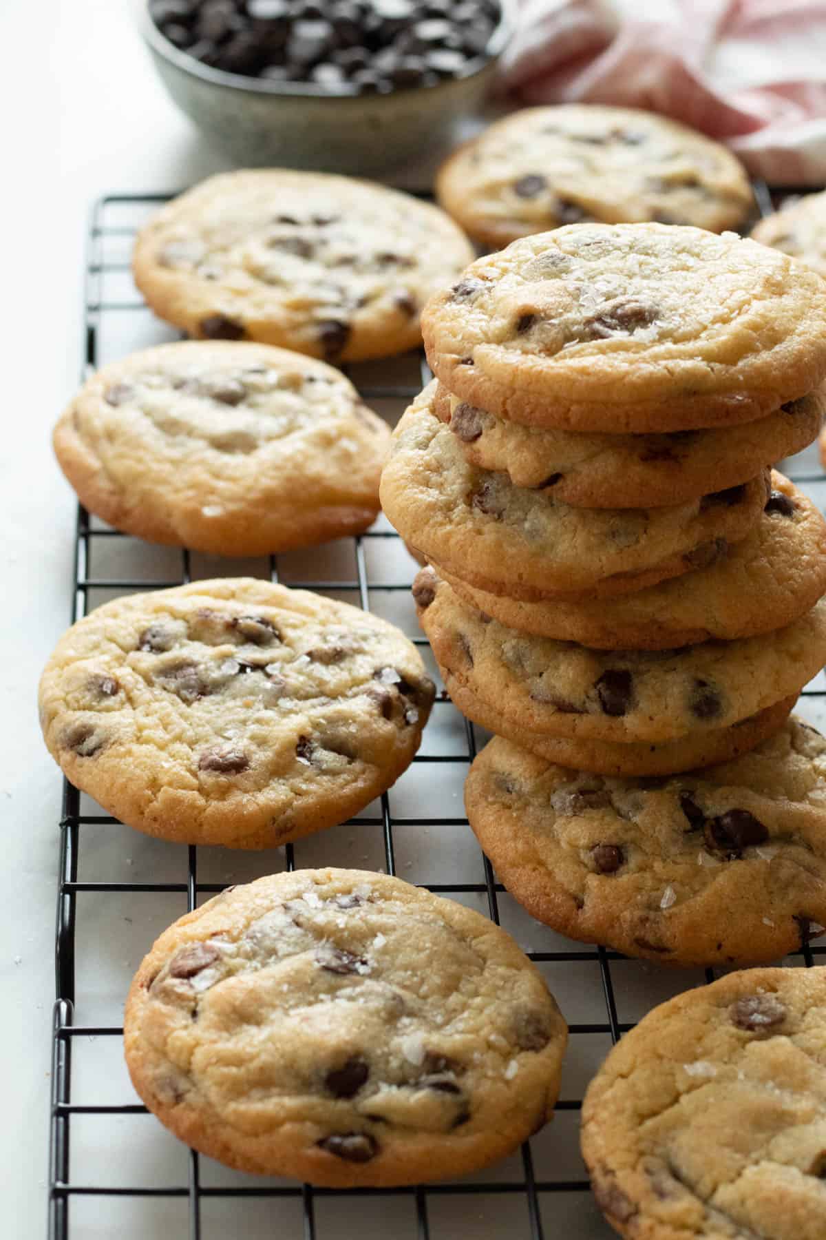 A stack of chocolate chip cookies on a cooling rack.