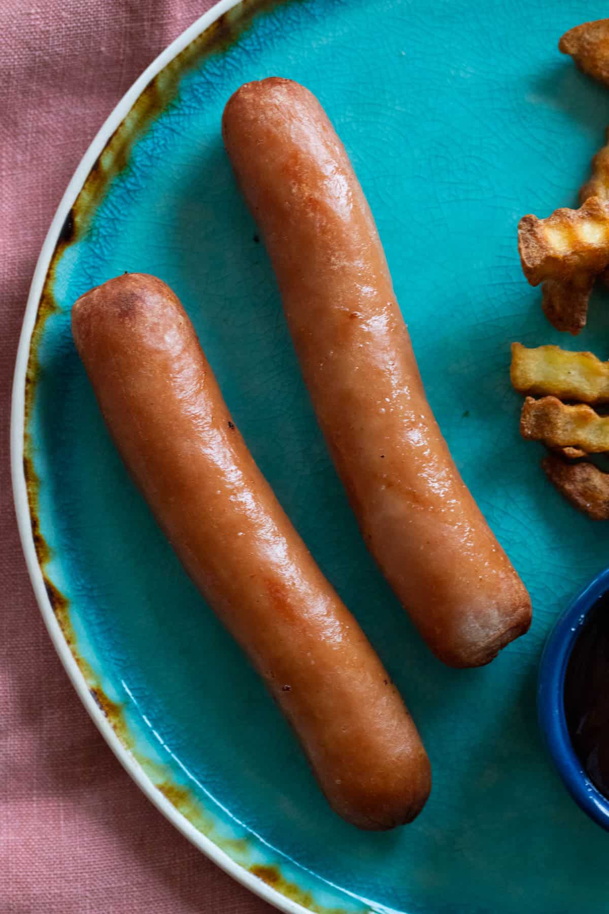 Cooked hot dogs on a blue plate.