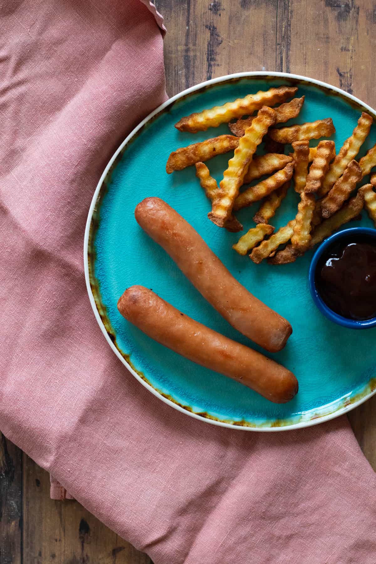 Cooked hot dogs on a blue plate.