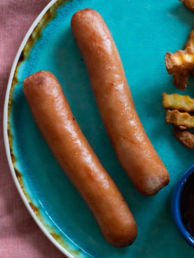 Cooked hot dogs on a blue plate.