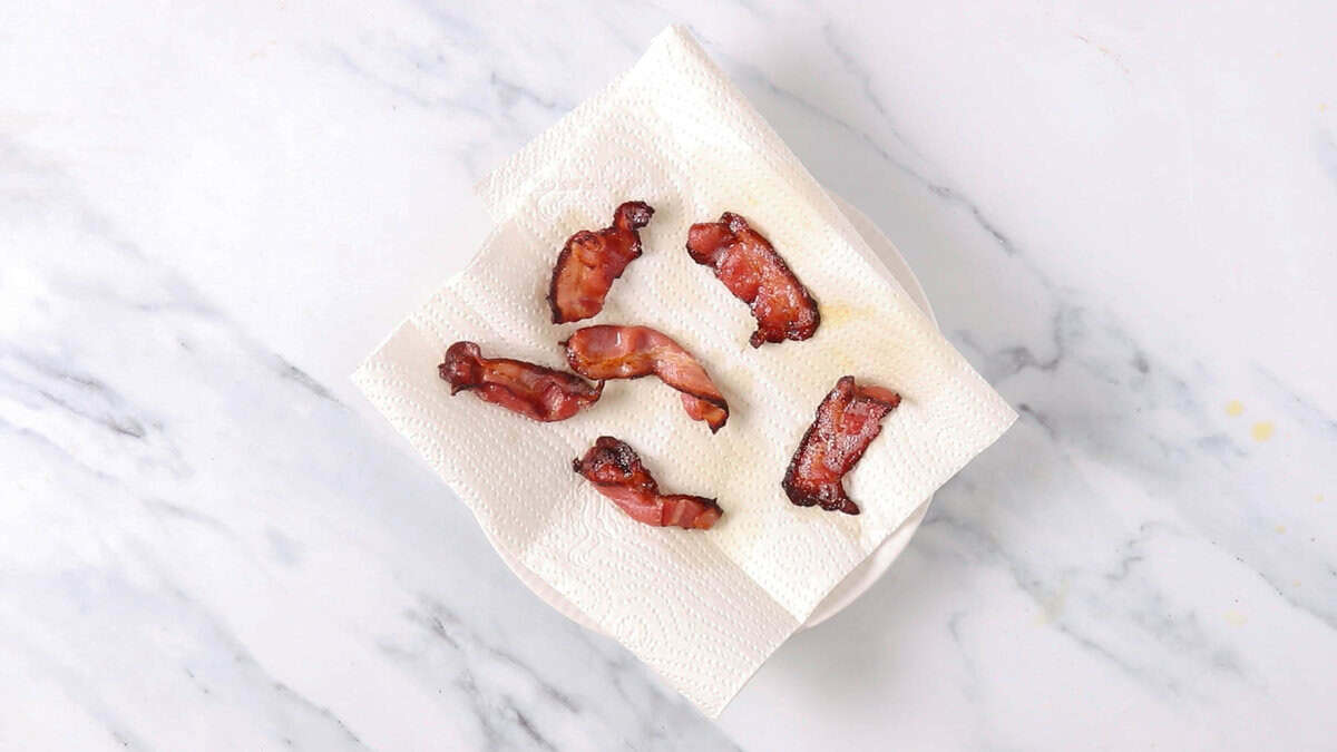 Air fried bacon slices placed on a parchment paper to crisp up.