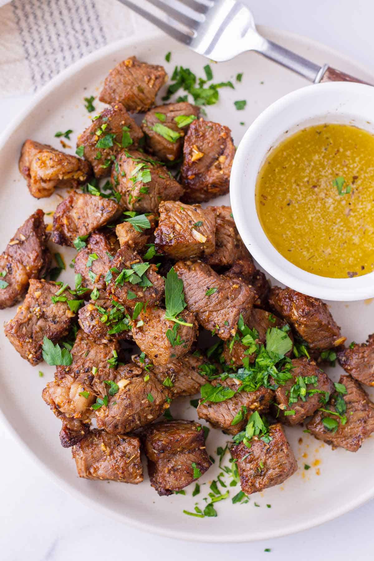 Air fryer steak bites on a plate with garlic butter.