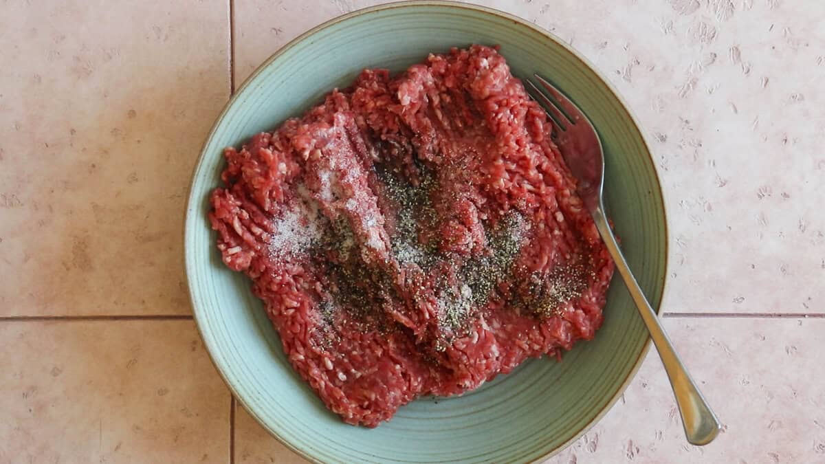 Ground beef and seasonings in a bowl before mixing.