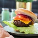 Air fryer hamburger in a bun topped with cheese and vegetables.