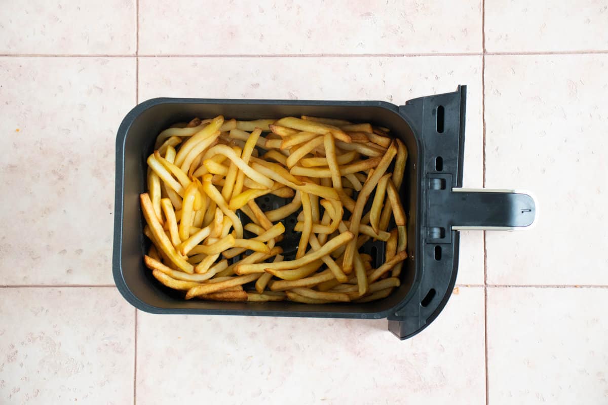 Leftover French fries in an air fryer basket.