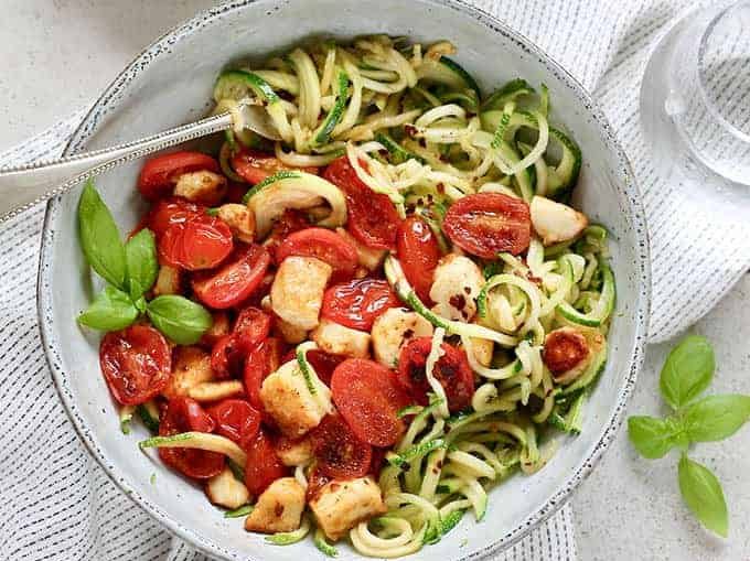 A bowl of zucchini noddles, halloumi and cherry tomatoes.