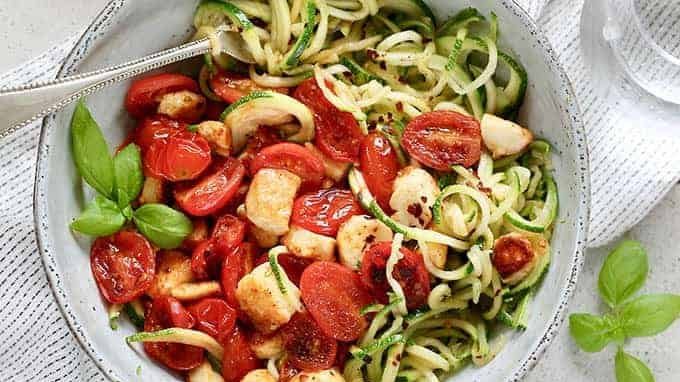 A bowl of zucchini noddles, halloumi and cherry tomatoes.