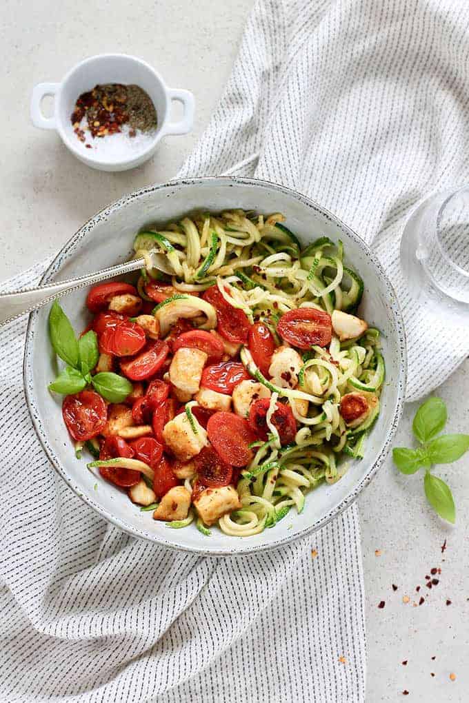 A bowl of zucchini noddles, halloumi and cherry tomatoes.