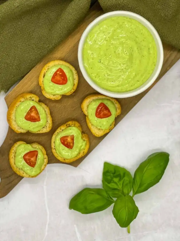 A bowl of pesto aioli and crostini topped with it.