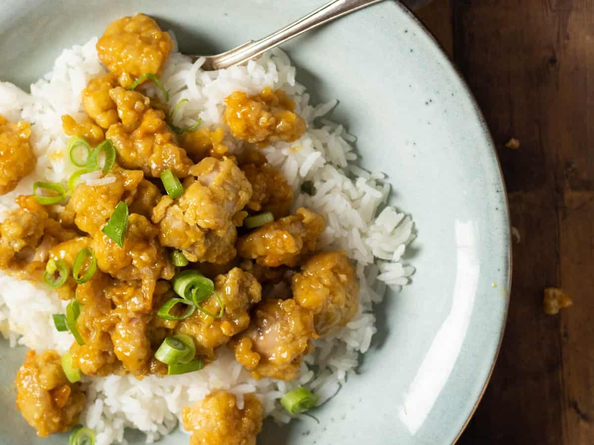 Air Fryer Orange Chicken over the rice on a plate.