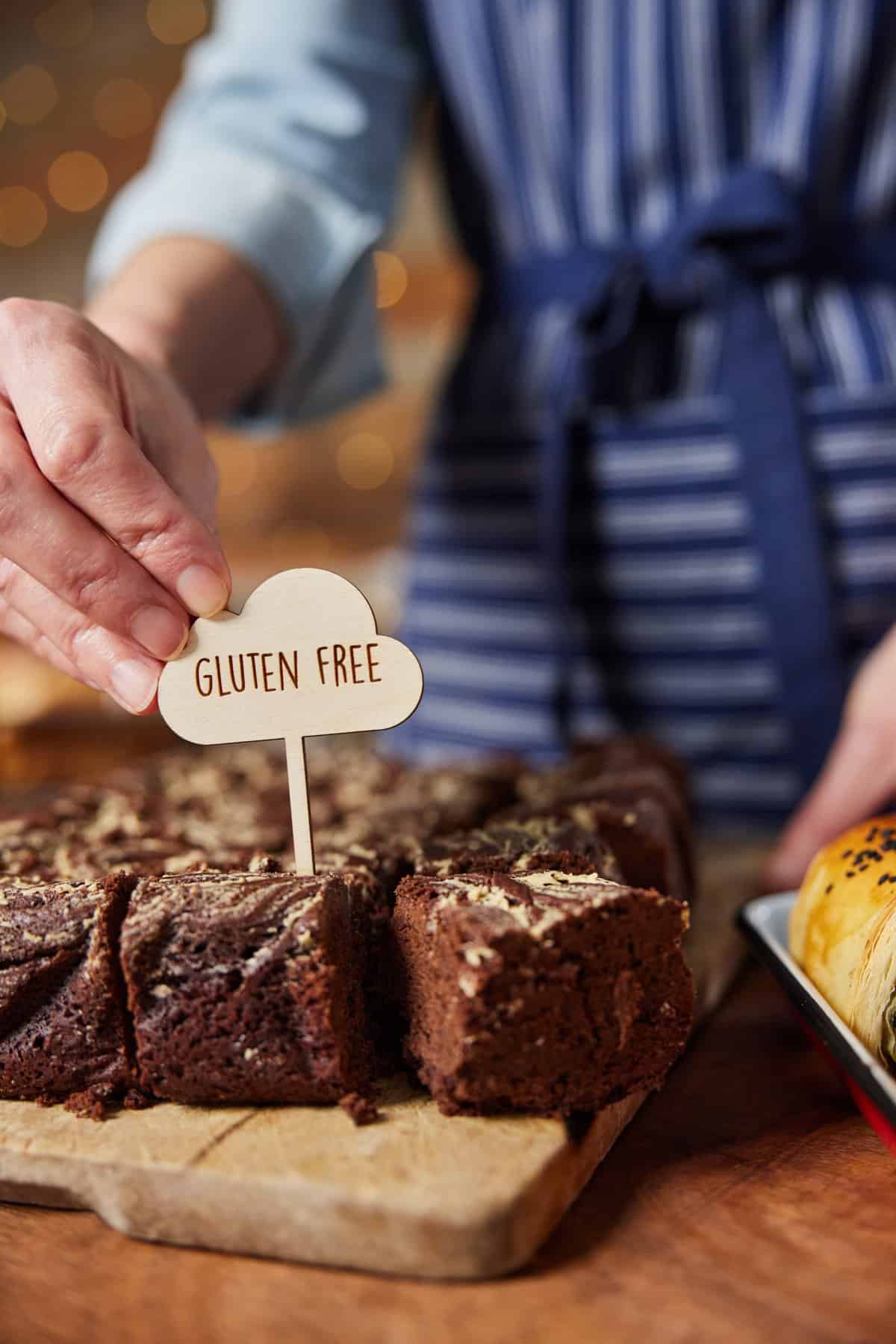 A sign with the text "gluten free" being set down in a piece of cake.