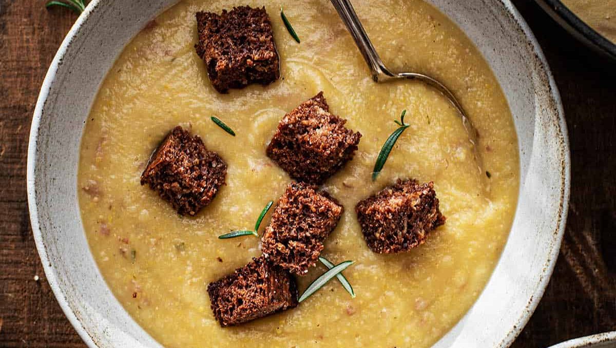 A bowl of cauliflower potato soup topped with dark bread croutons.