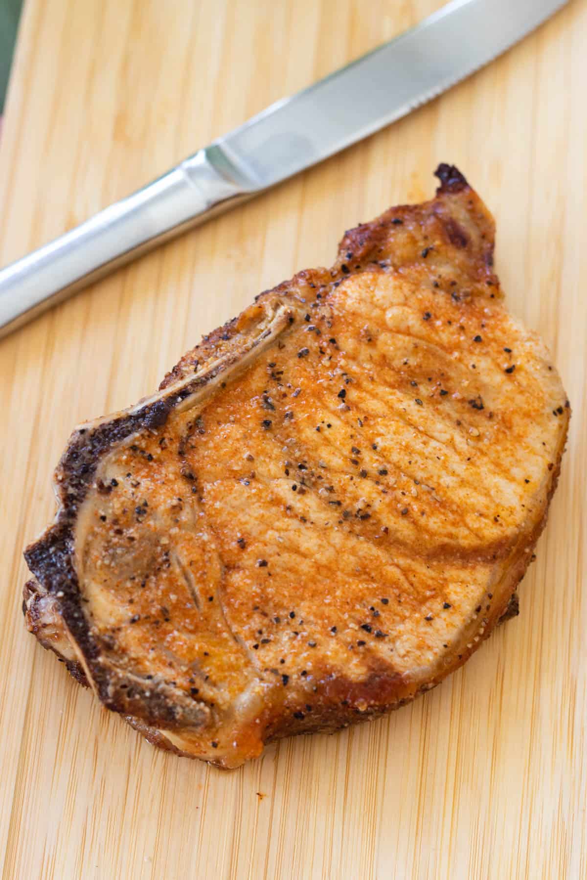 A pork chop on a small chopping board.